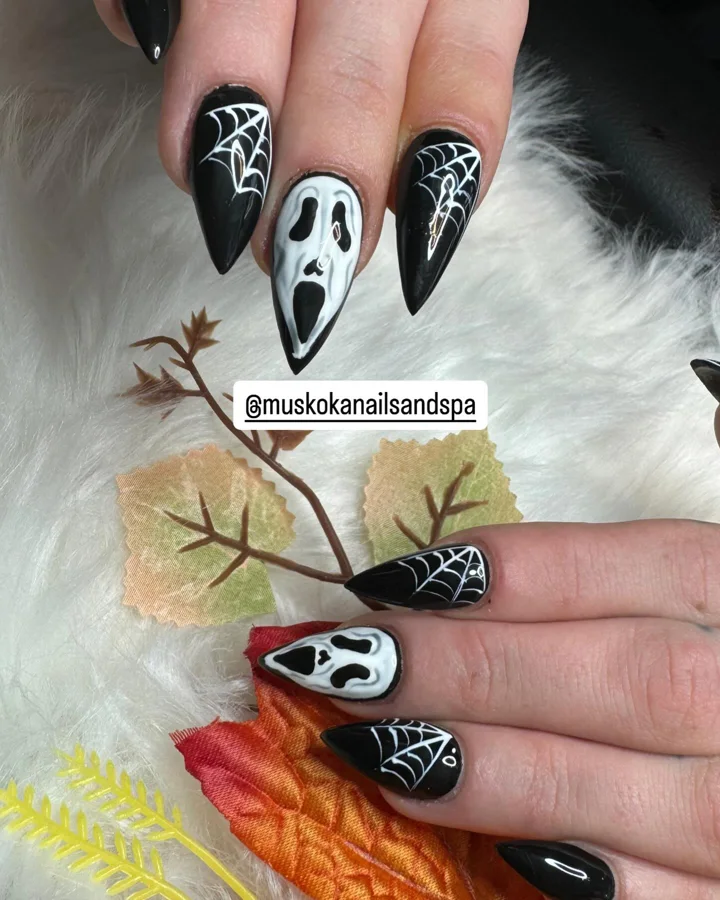Black stiletto nails with white spiderweb and ghost designs by Muskoka Nails & Spa