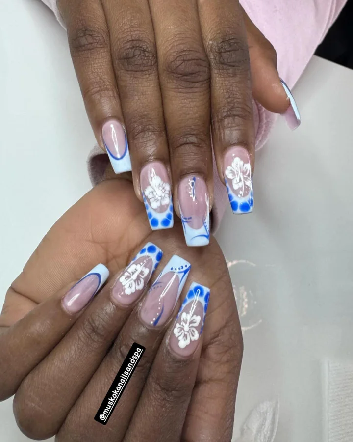 Blue French tips with white hibiscus flowers by Muskoka Nails & Spa