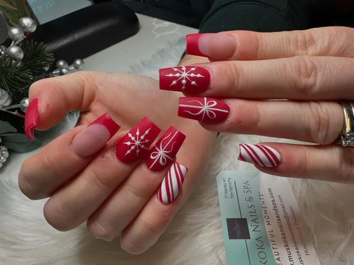Red square nails with white stripes, bows and snowflakes by Muskoka Nails & Spa
