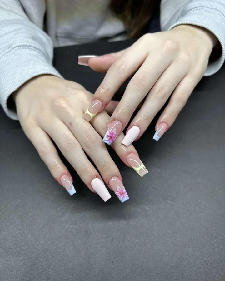 Pastel yellow and blue French tips with pink flower accents by Muskoka Nails & Spa