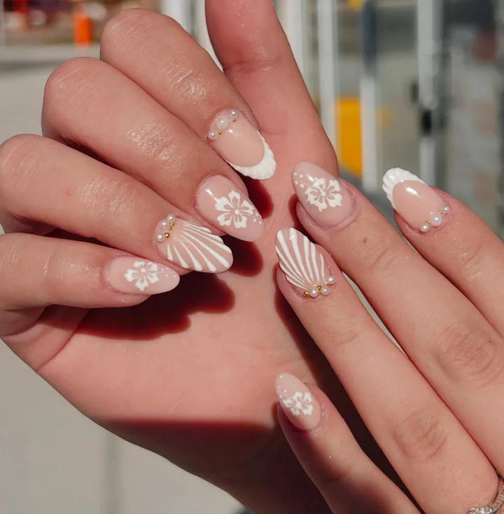 Soft nude nails with white flowers, pearl details and shell designs by Muskoka Nails & Spa