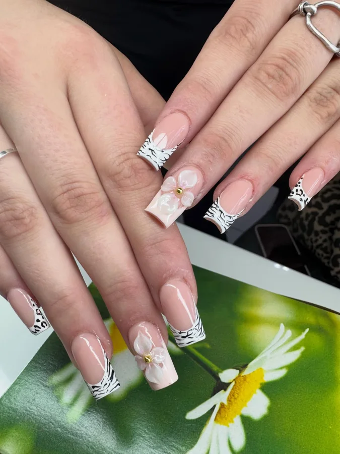 Black and white patterned French tips with sculpted white flowers by Muskoka Nails & Spa