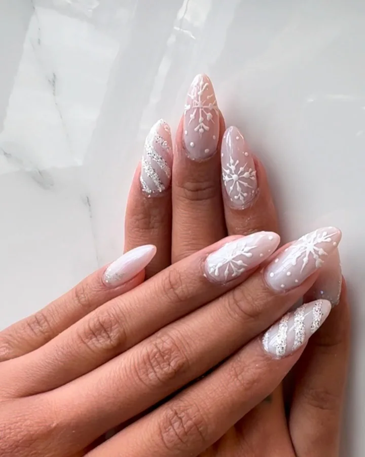 Pale pink almond nails with white snowflakes and silver shimmer by Muskoka Nails & Spa